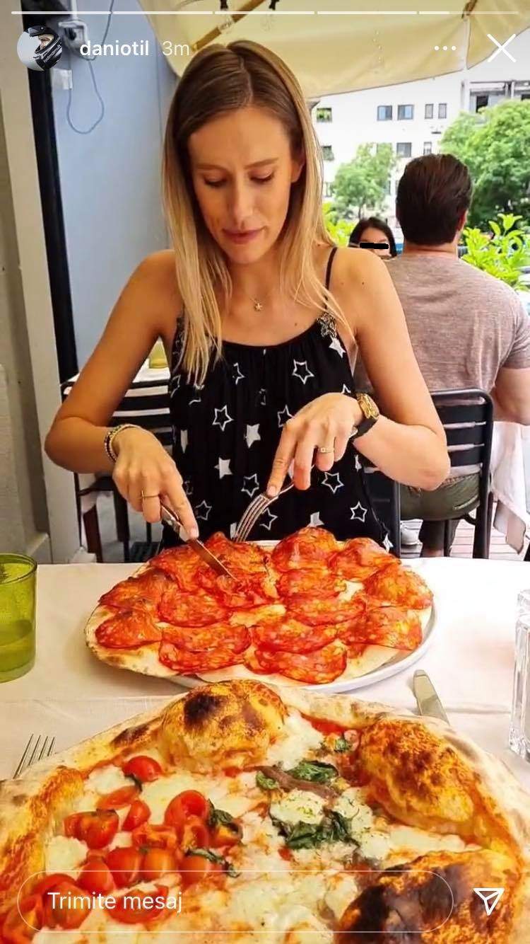 Gabriela Prisăcariu mănâncă pizza la o terasă, în Milano. Vedeta poartă o rochie neagră cu steluțe albe.