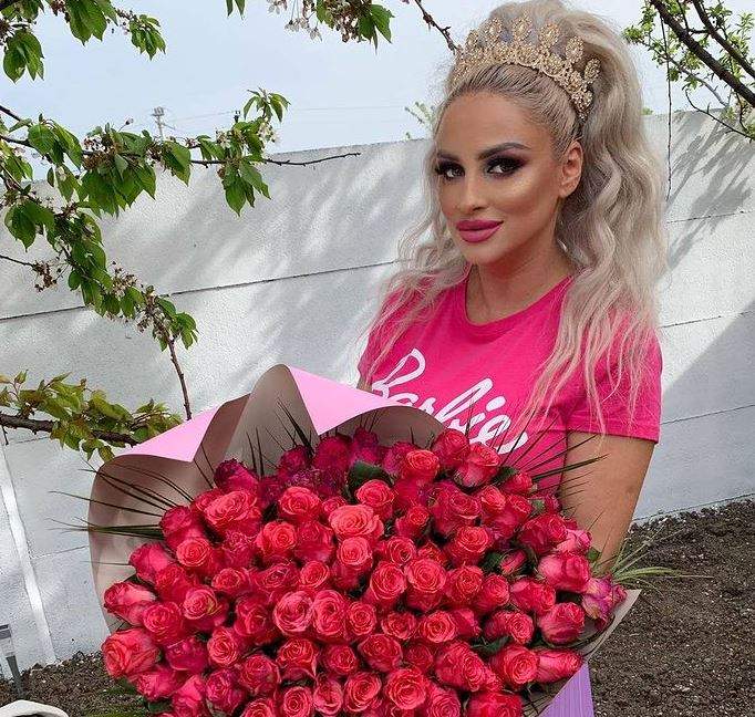 Sânziana Buruiană poartă tricou roz și ține un buchet de flori în mână.