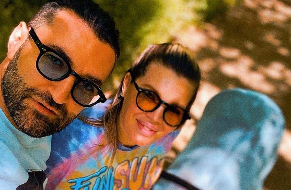 Smiley și Gina Pistol într-un selfie. Amândoi zâmbesc și poartă ochelari de soare. Lângă ei este căruciorul de copii bleu al fiicei lor, Josephine.