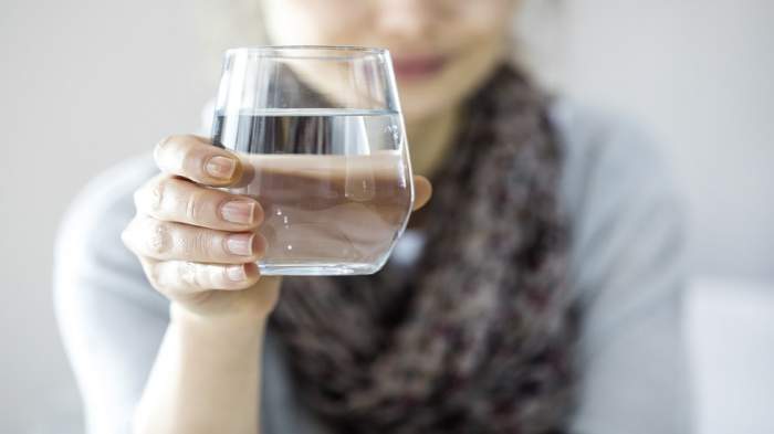 O femeie care ține în mână un pahar de apă