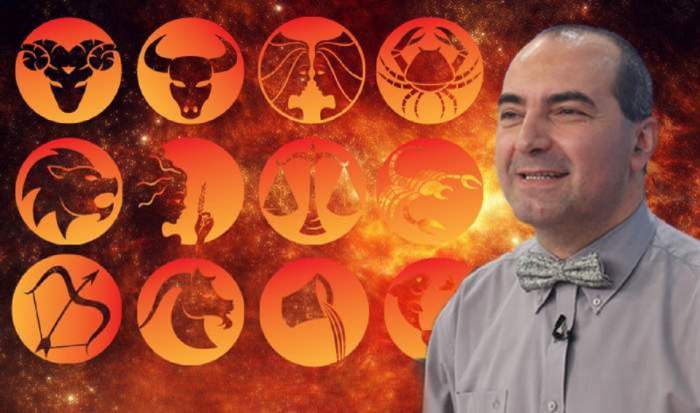Astrologul Remus Ionescu poartă o cămașă și un papion gri. Lângă el sunt simboluri cu toate zodiile.
