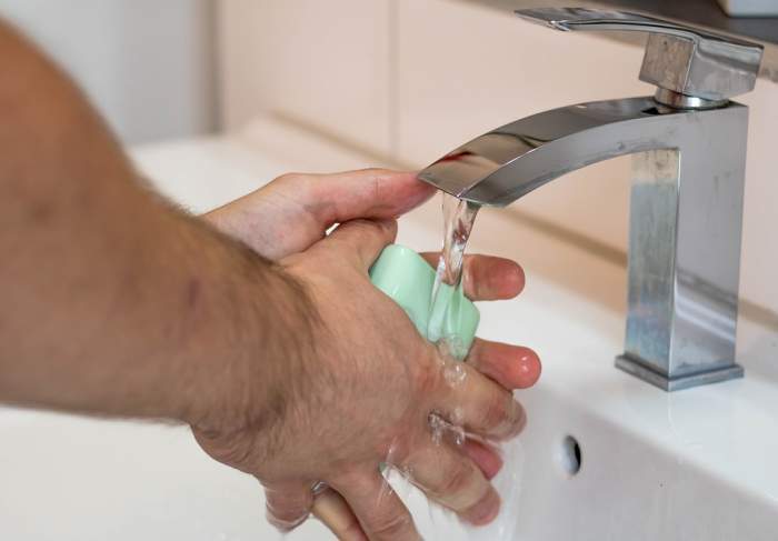 Un barbat care se spală cu săpun pe mâini