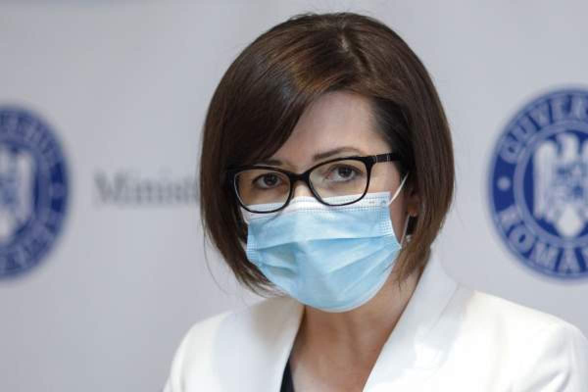 Oana Mihăilă, îmbrăcaă în alb, cu ochelari și mască de protecție pe față