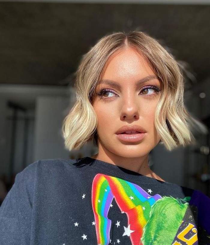 Alexandra Stan își face un selfie cu gura întredeschisă și poartă tricou negru cu model cu curcubeu.