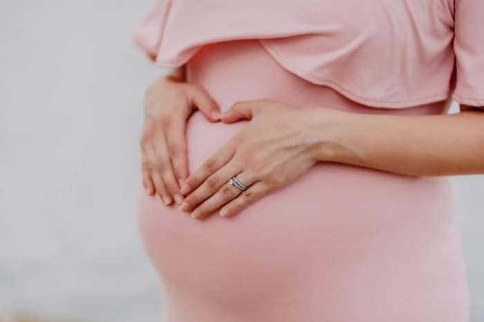 femeie însărcinată cu mâinile e burtică