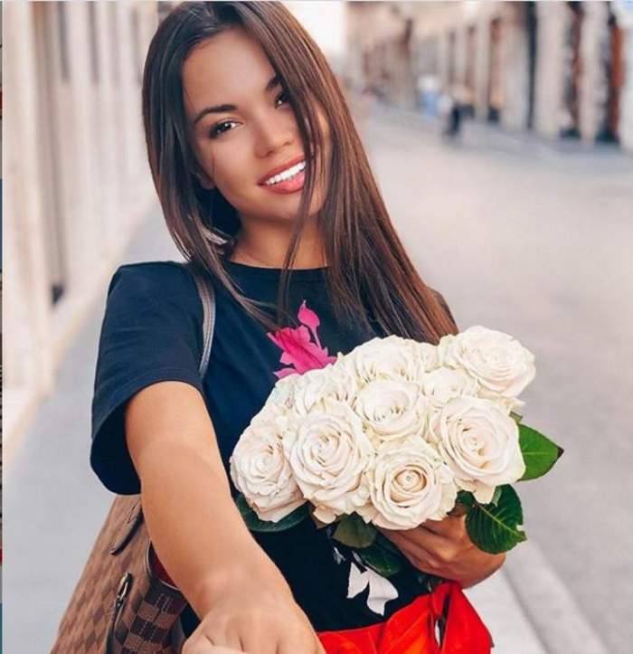 Denisa Hodișan, cu un buchet de flori albe în brațe, zâmbitoare