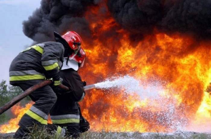 Doi pompieri care sting un incendiu