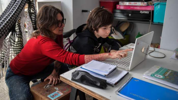 O mamă care își ajută copilul la cursurile online
