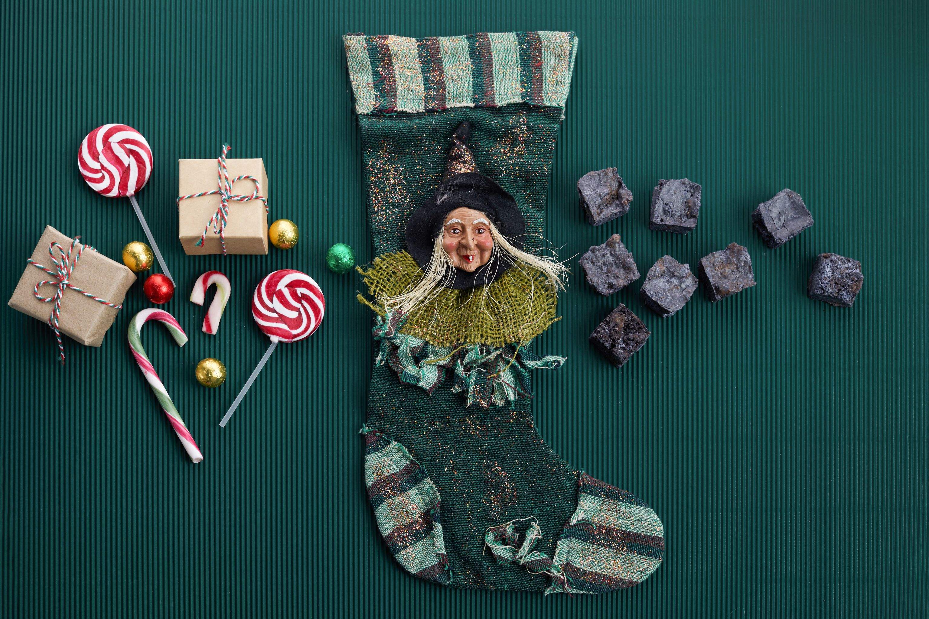 Vrăjitoarea La Befana cu un ciorap și dulciuri în fundal.