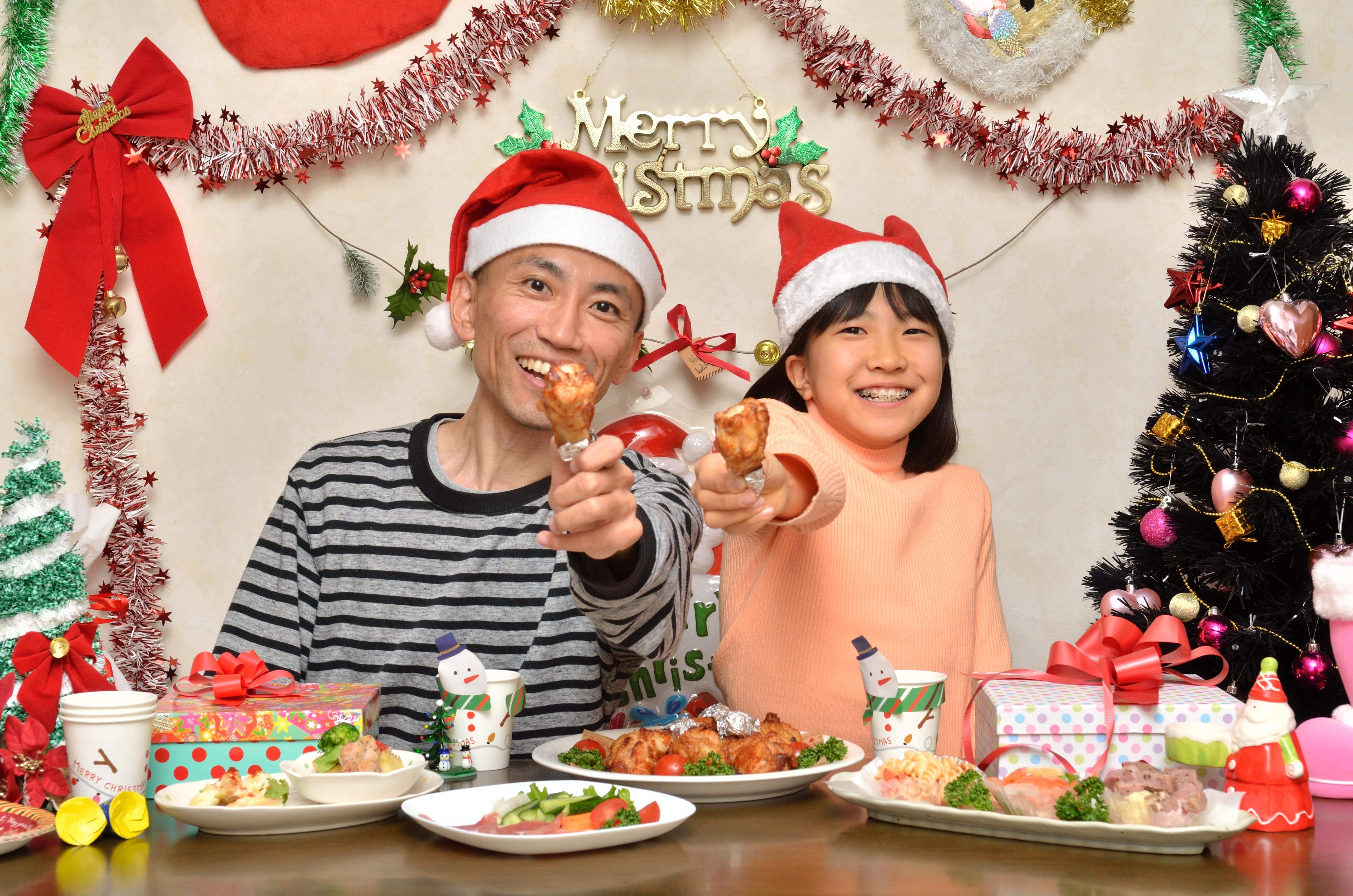 Un părinte și copilul său se bucură la o petrecere de Crăciun cu mâncare de la KFC.
