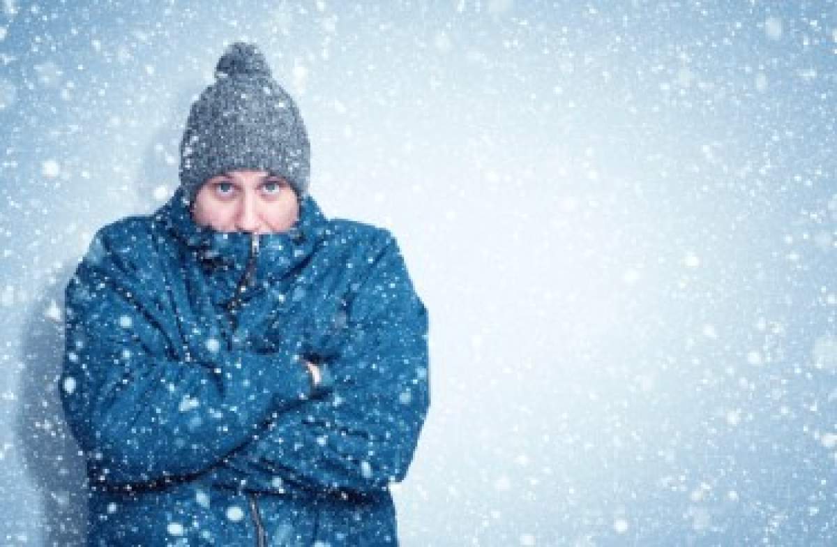 barbat îmbrăcat de iarnă care tremură de frig în ninsoare