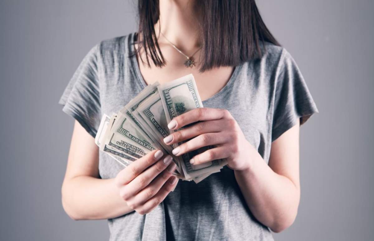 femeie care ține bani în mână