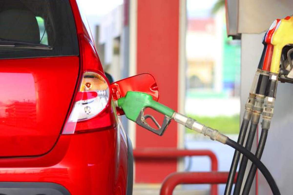 O mașină roșie într-un peco în timp ce se alimentează de la pompă cu  mâner verde