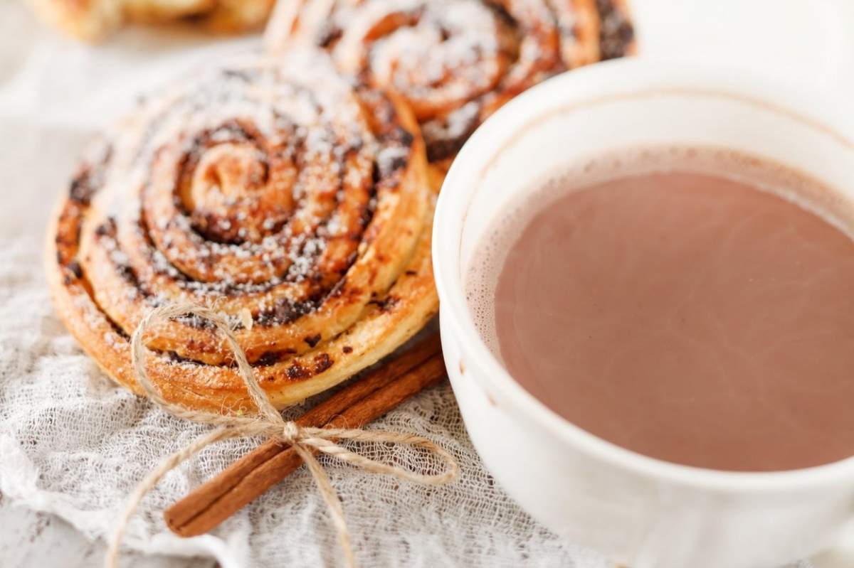 un rulou cu scorțișoară și o cafea