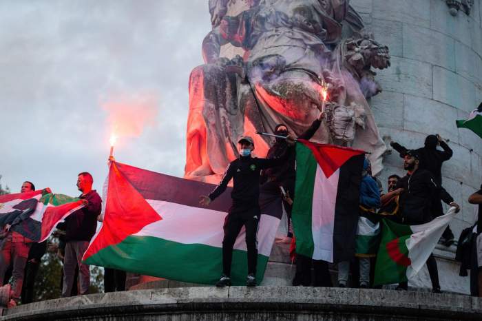 Persoane care flutură steagul Palestinei în semn de susținere în Paris.