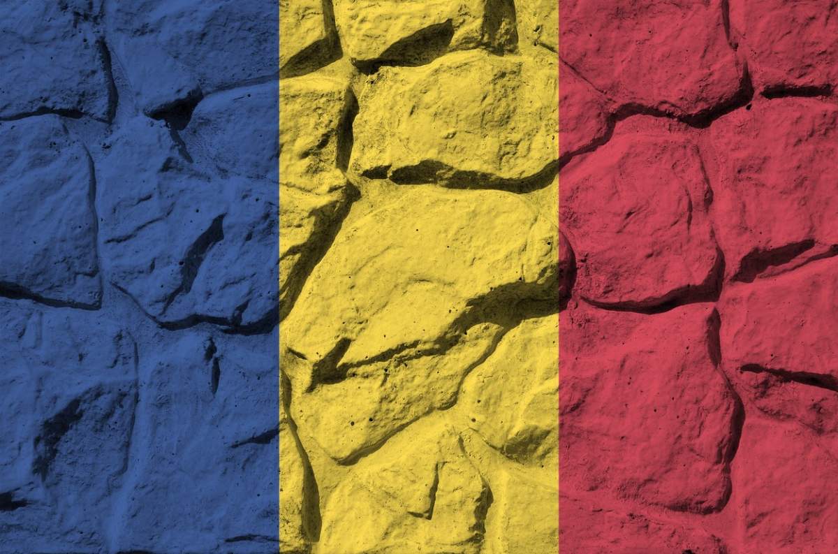 Steagul României reprezentat în culori de vopsea pe un zid de piatră vechi. Banner texturat pe fundal de perete de stâncă