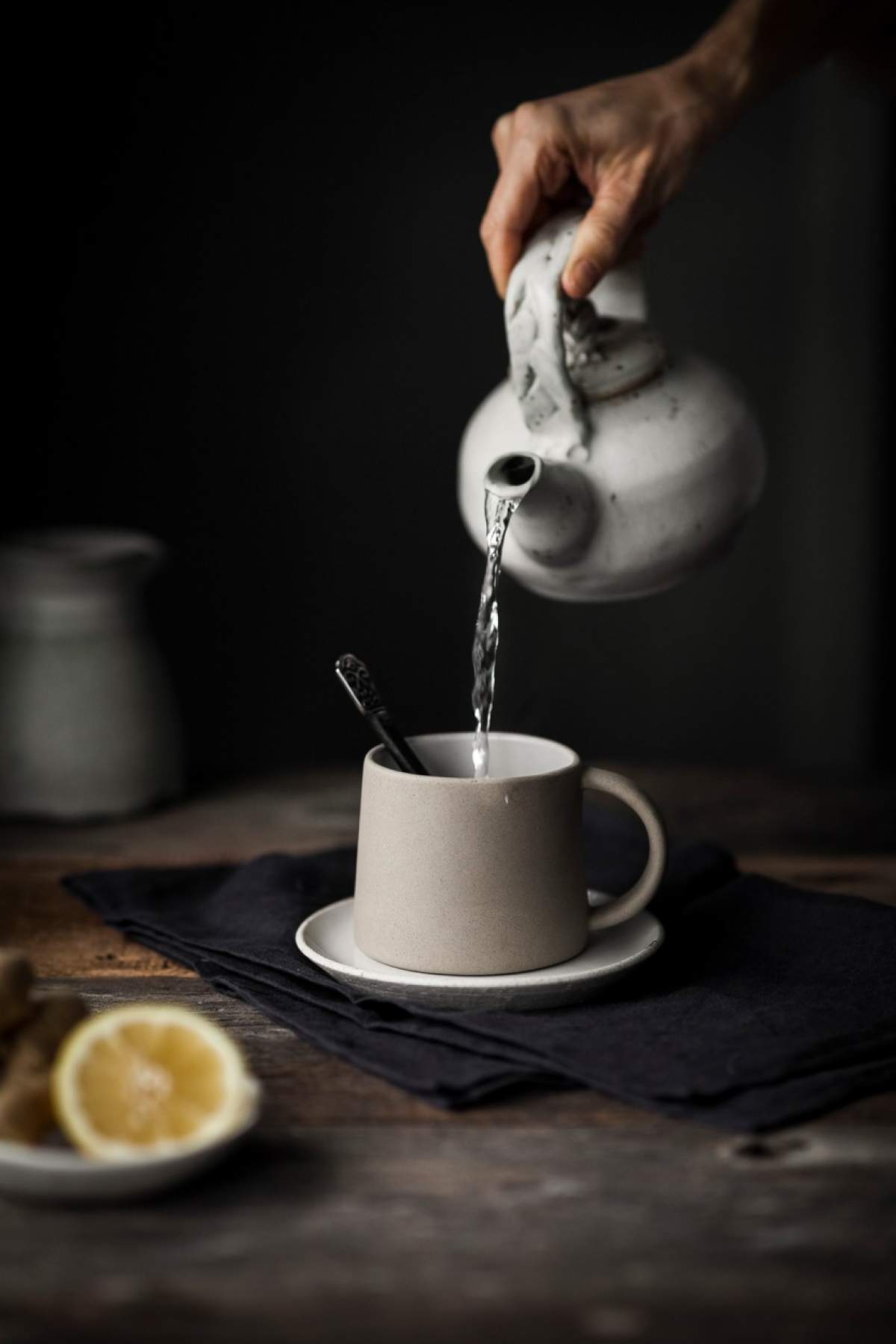 O persoană care toarnă apă fierbinte într-o cană de ceai cu lămâie