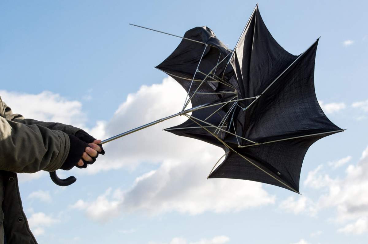 Bărbat ținând o umbrelă în vânt puternic