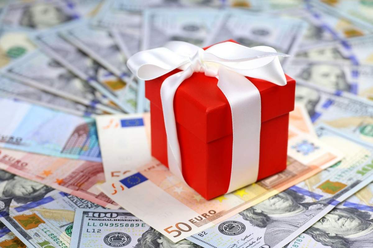 Cutie cadou roșie înfășurată cu panglică albă pe fundal euro și dolari SUA