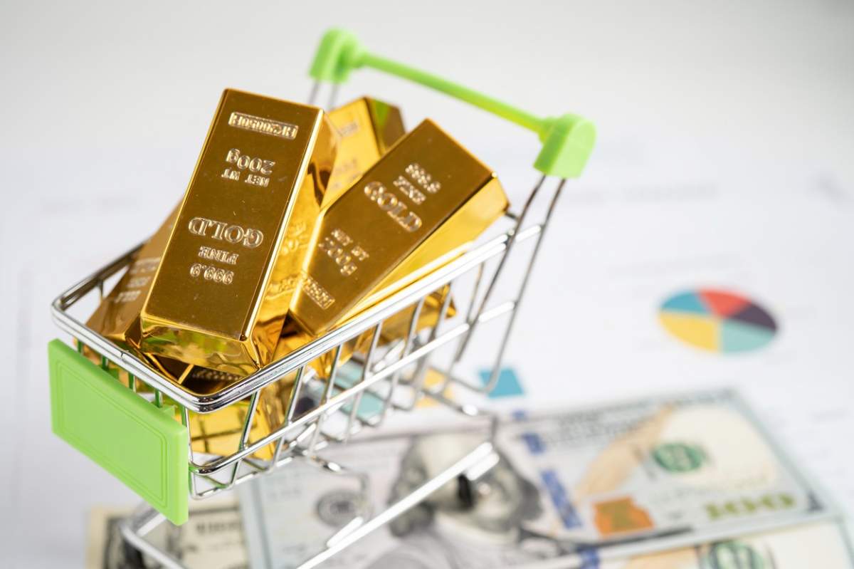 Lingou de aur în coșul de cumpărături pe bancnote în dolari americani, bani și grafic