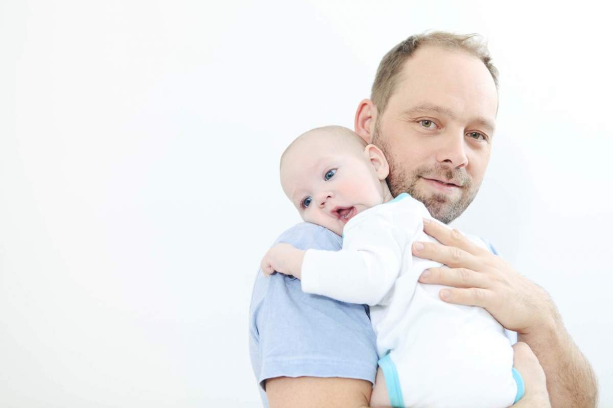 Un bărbat ține un bebeluș în brațe