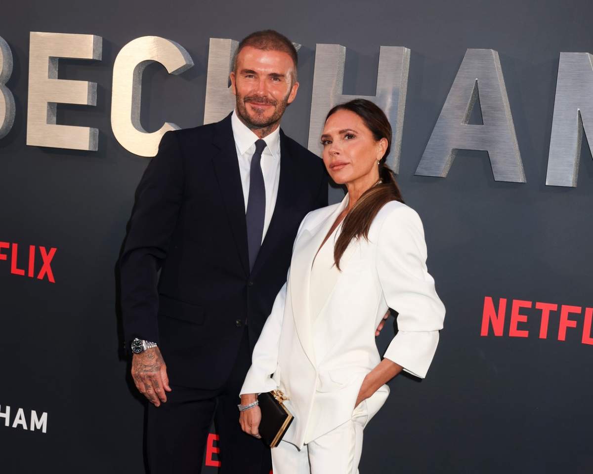 David Beckham în costum negru și soția lui, Victoria Beckham, îmbrăcată în alb