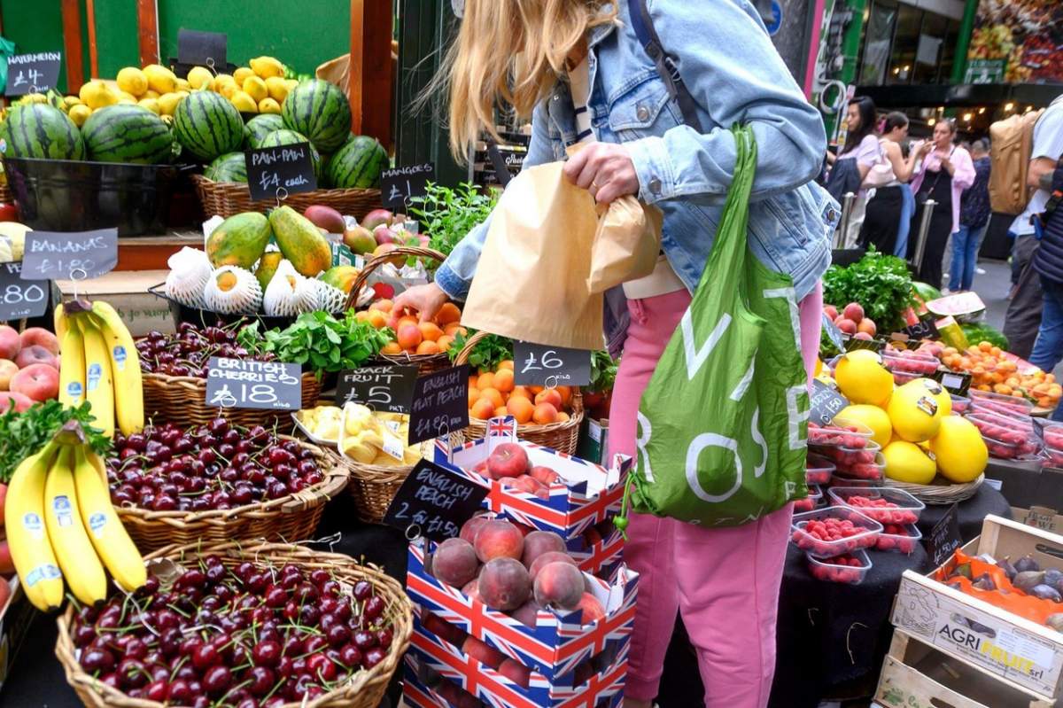 Femeie la cumpărături la un stand de fructe.