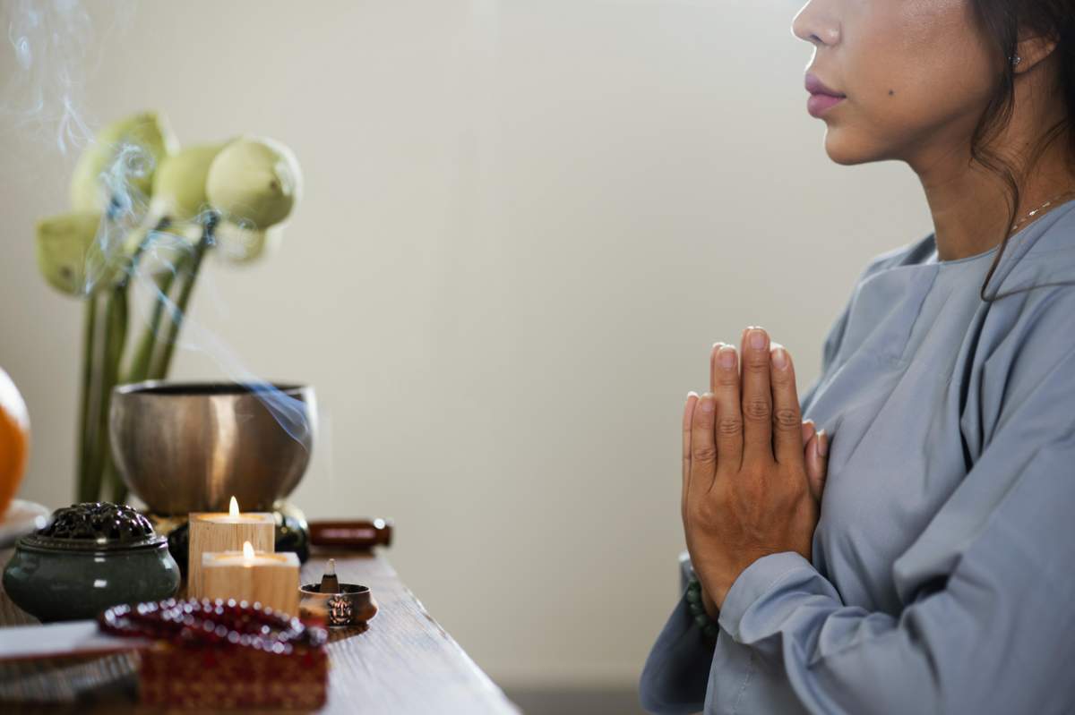 Vedere laterală femeie care se roagă în fața lumânărilor