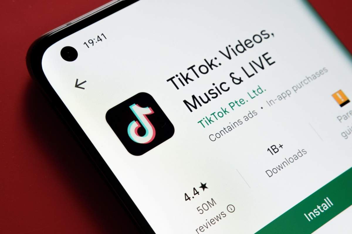 Aplicația TikTok văzută în Magazinul Google Play pe ecranul smartphone-ului plasat pe fundal roșu