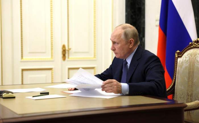 Președintele rus Vladimir Putin la o masă cu foi în mână