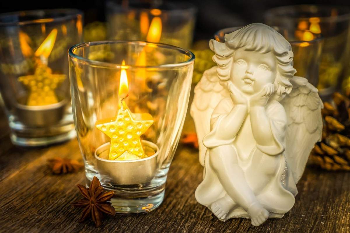 Înger de Crăciun și lumânări aurii strălucitoare în sticlă