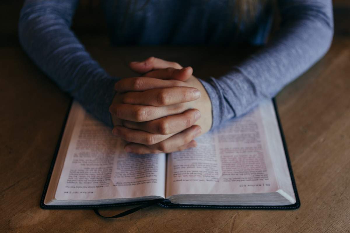 o persoană care se roagă și o biblie