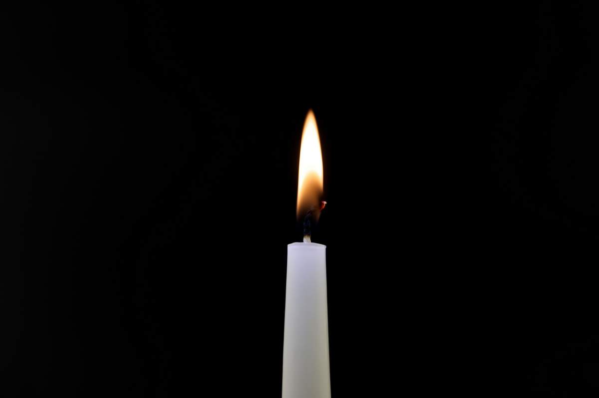 Prim-plan al flăcării unei lumânări pe un fundal negru