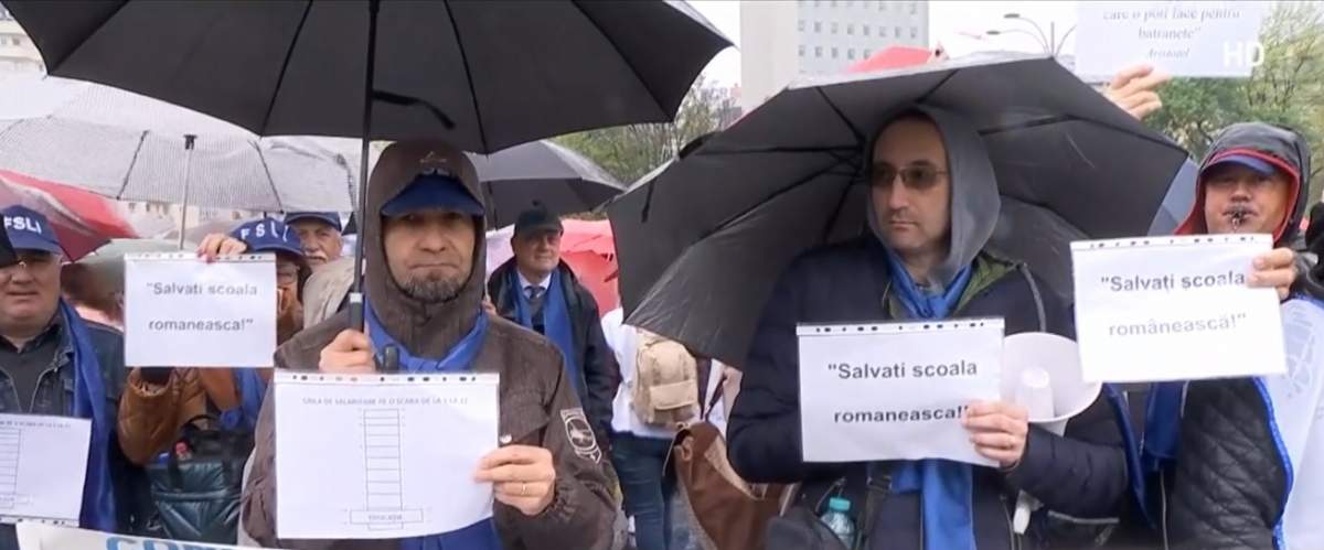 profesori și angajați din școli care țin mesaje de protest în mână