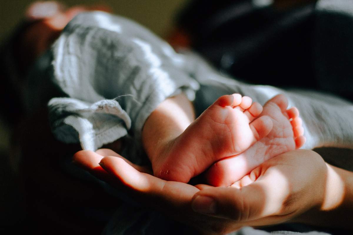 picioare de bebeluș în mâna unei mame.