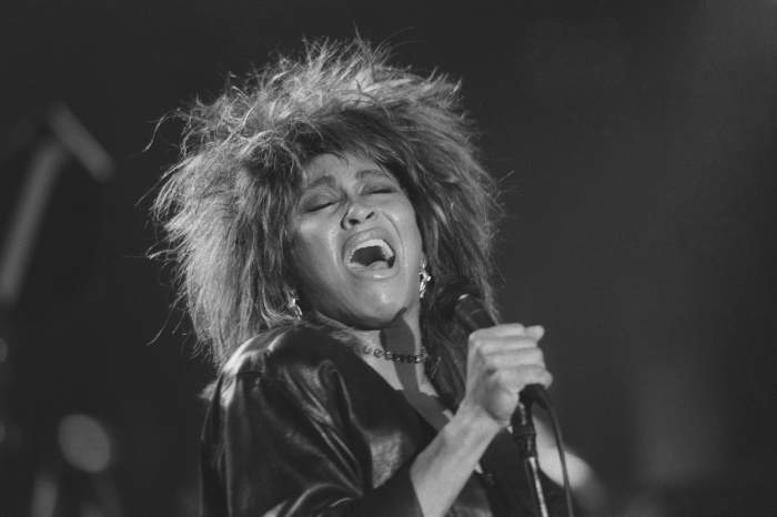 Tina Turner pe scenă cu microfonul.