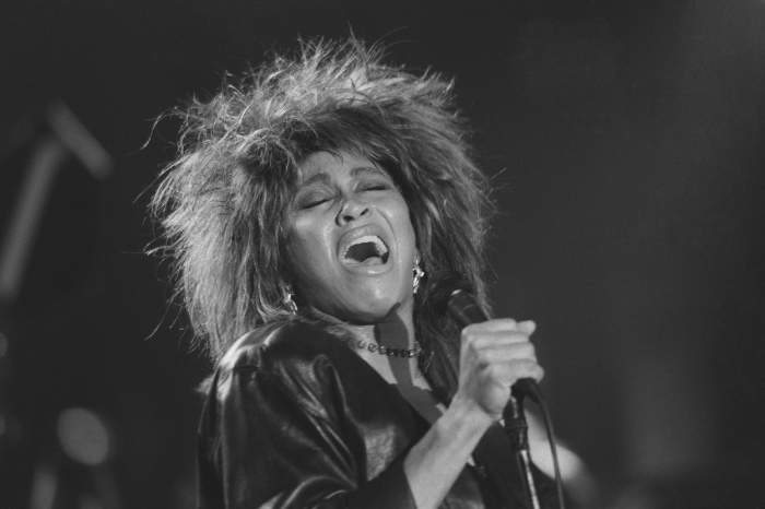 Tina Turner pe scenă cu microfonul.