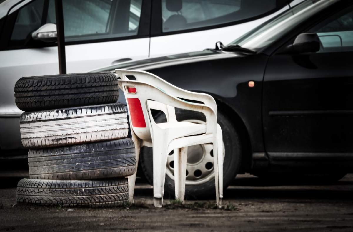 Scaune albe din plastic care stau lângă anvelope și mașini