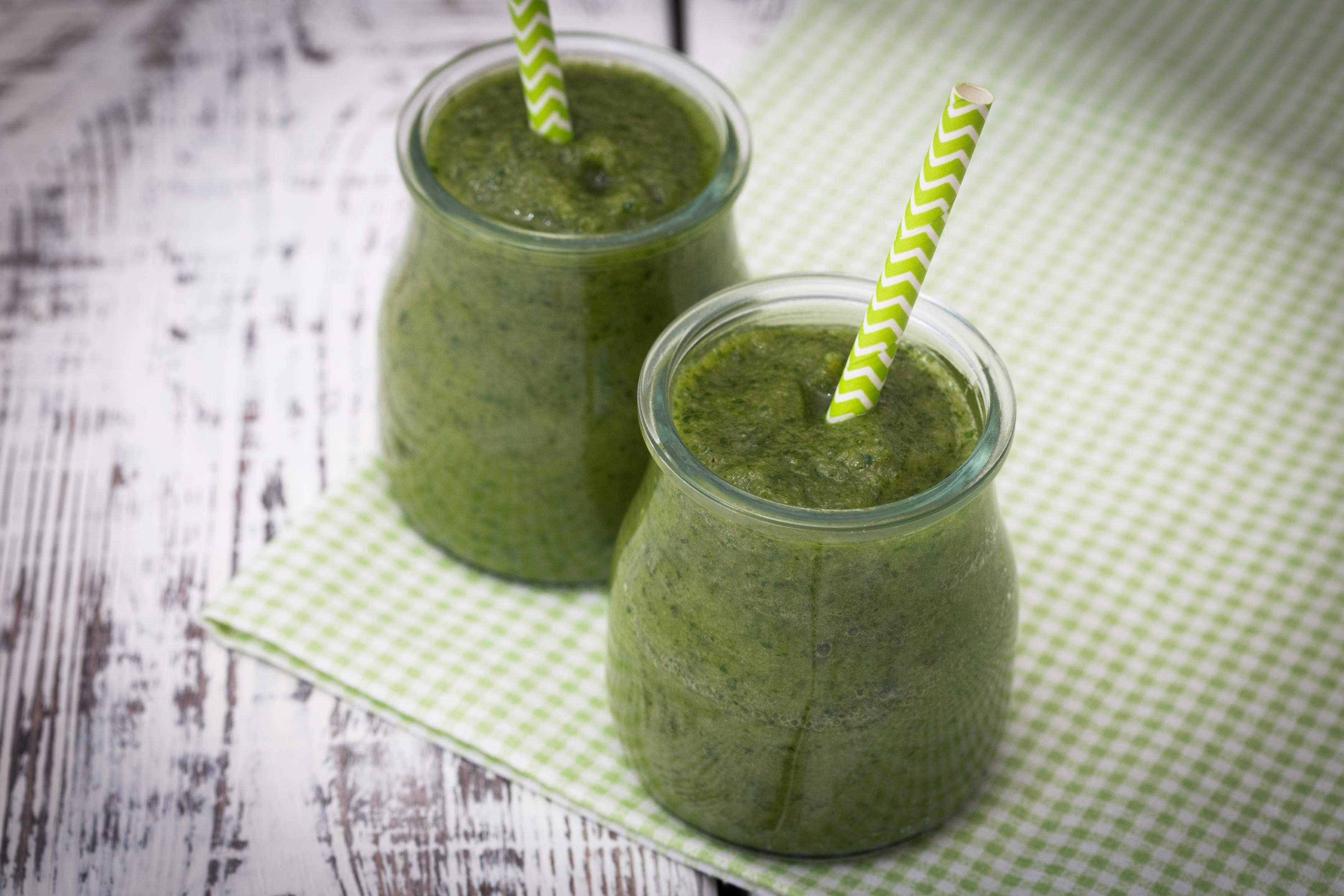 Smoothie verde cu mere, banane și spanac pe un fundal deschis