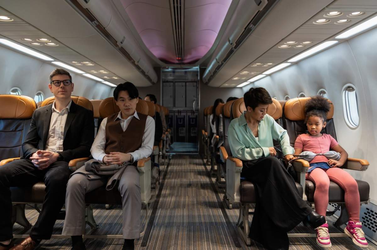 Pasageri multietnici care stau în cabina avionului în timpul zborului