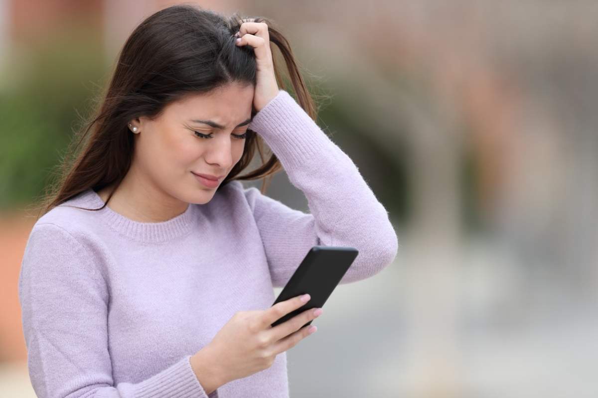 Adolescenta trista care se plânge citind mesaje telefonice pe stradă