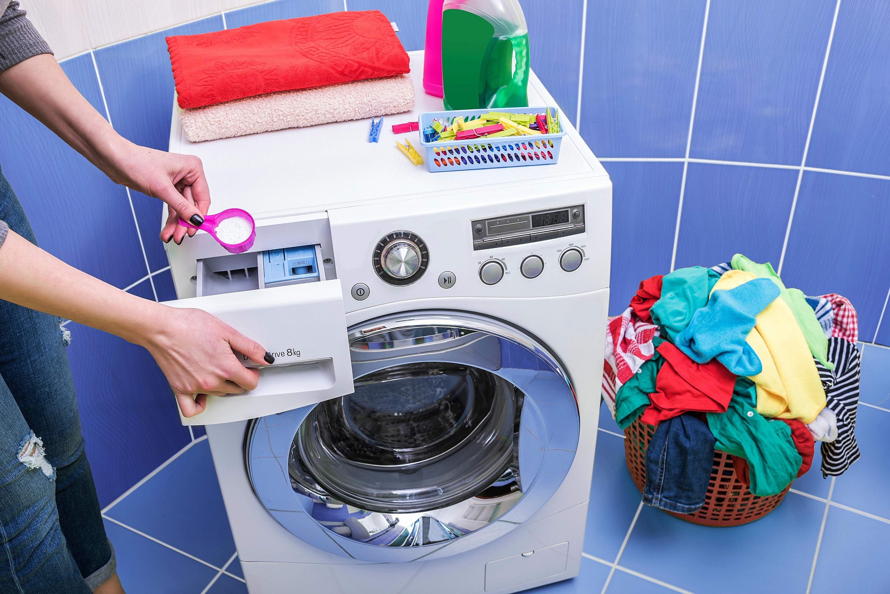 O femeie pune detergent pudră în mașina de spălat