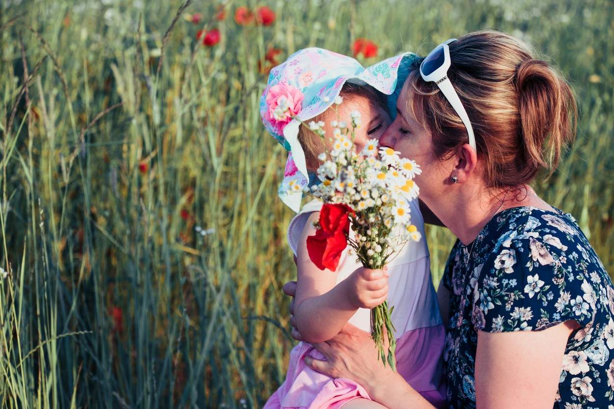 Mama și fiica ei mică în câmpul de flori sălbatice