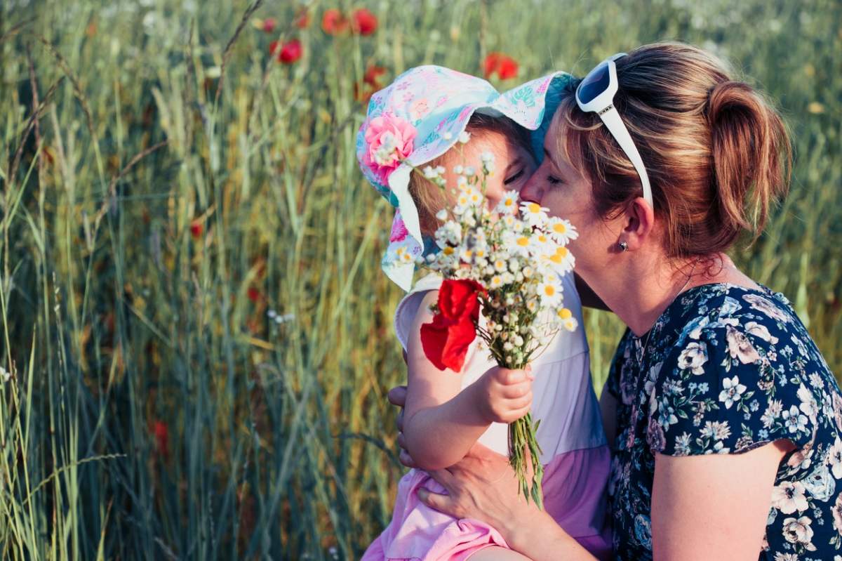Mama și fiica ei mică în câmpul de flori sălbatice