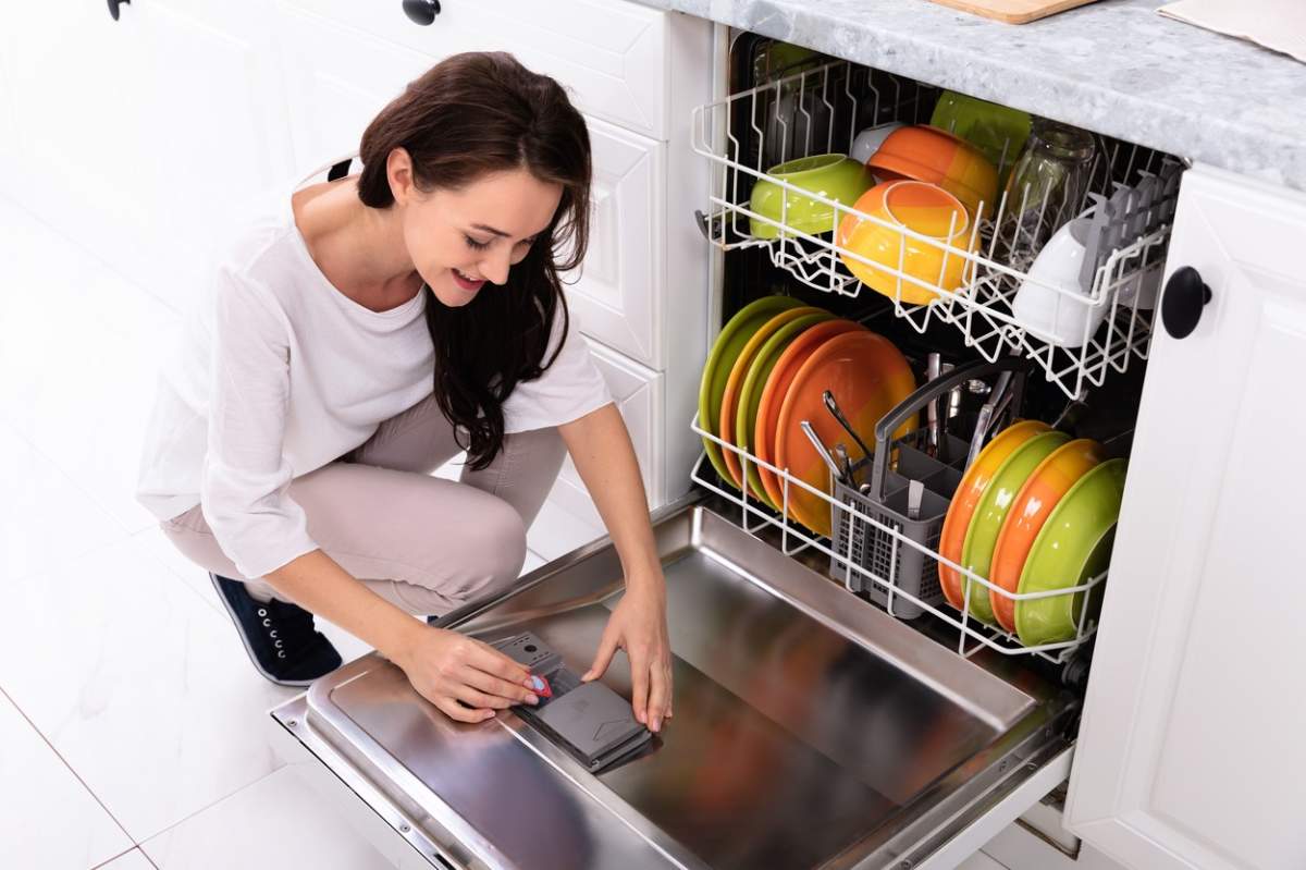 O femeie care pune detergent în mașina de spălat vase