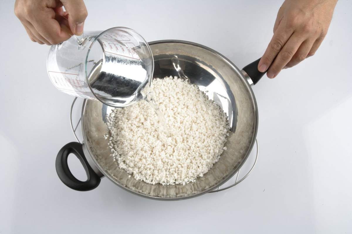 Se toarnă apă peste orez la fiert în oală