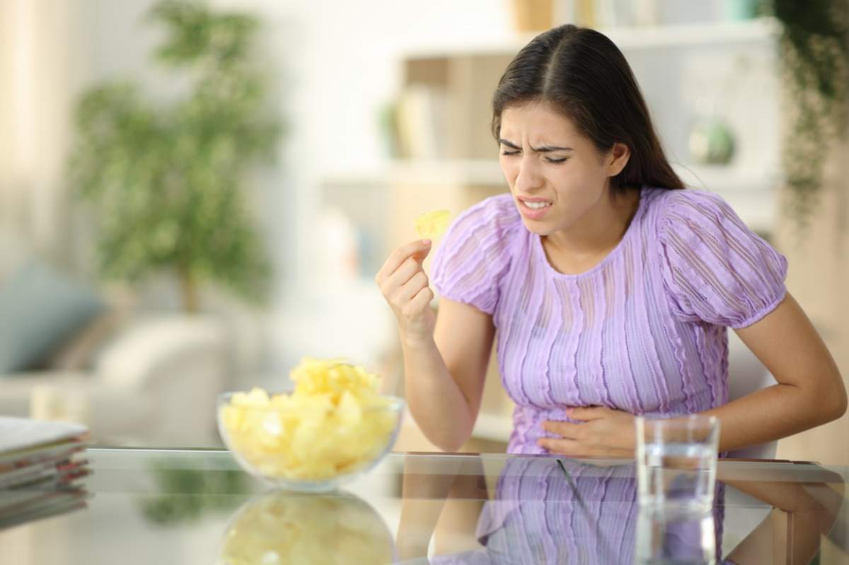 Femeie care suferă de dureri de stomac mâncând