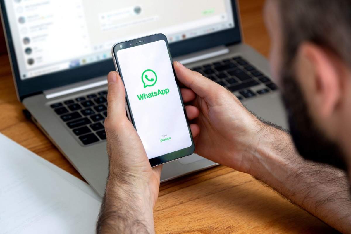 Sigla aplicației WhatsApp pe ecranul telefonului în mâinile unui bărbat.