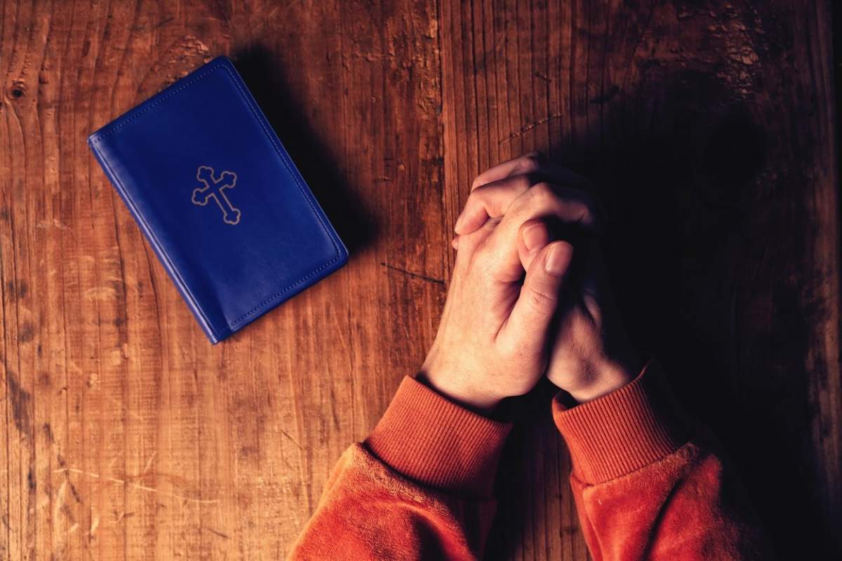 Fotografie cu o carte de rugăciuni și o persoană care se roagă