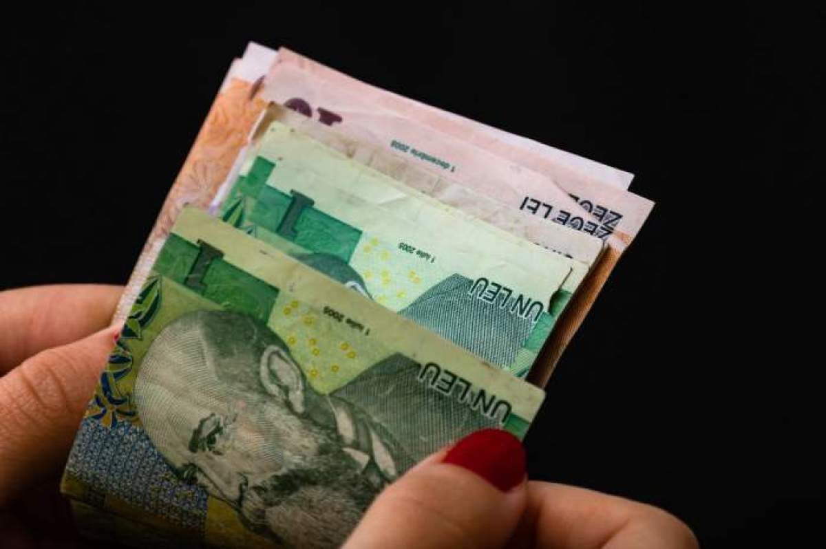 mana de femeie care numara bani pe fundal negru